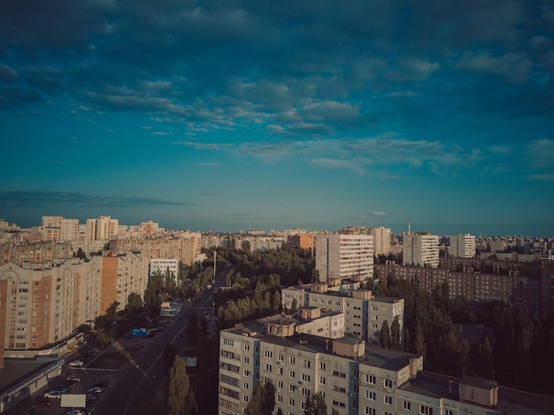 日光の下で成長する都市の空中写真曇り空の下で家や道路がある市内中心部の新しい複合ビルのドローンビュー