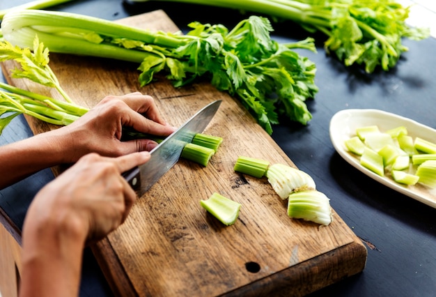 Aerial view of hands with knife cutting celery