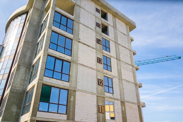 Aerial view of high residential apartment building with storey numbers on wall under construction. Real estate development.