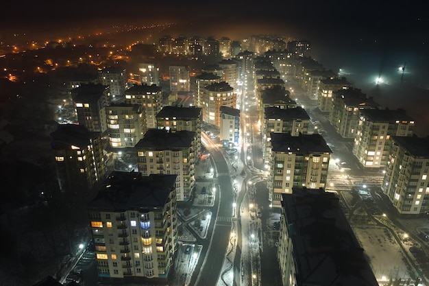 夜の都市住宅地の高層マンションと明るく照らされた通りの航空写真暗い都市景観