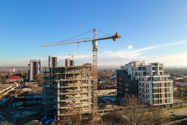 Aerial view of high tower crane and residential apartment buildings under construction. Real estate development.