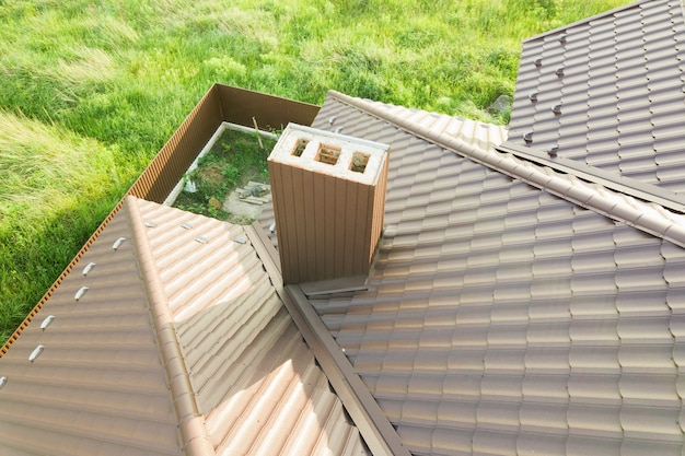 Aerial view of house roof structure covered with brown metal tile sheets.