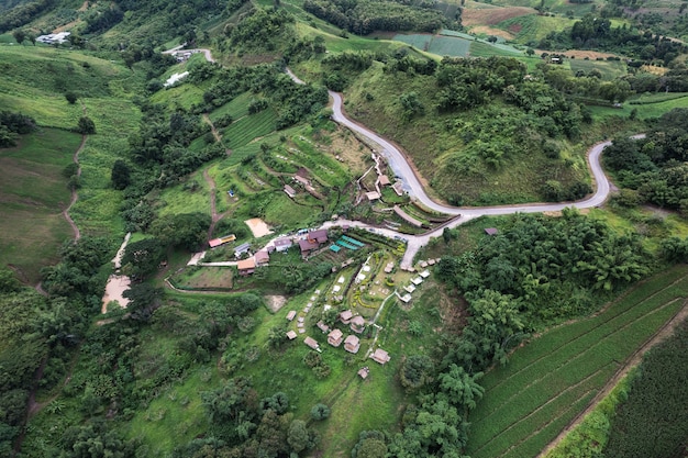 Aerial view of hut resort on hillside among the mountain in tropical rainforest on rainy day at Thailand