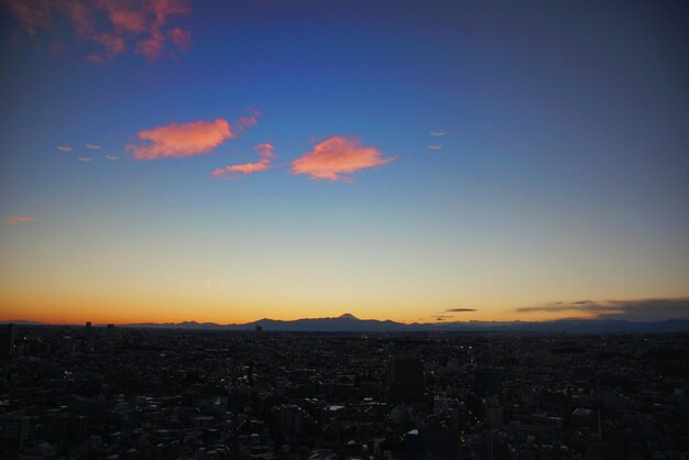 Aerial view of illuminated cityscape against sky at sunset