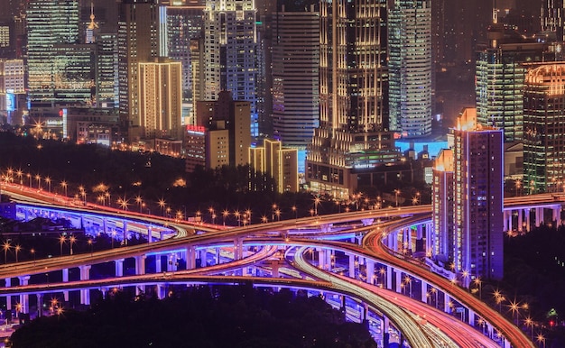 Aerial view of illuminated multiple lane highway and buildings in city at night