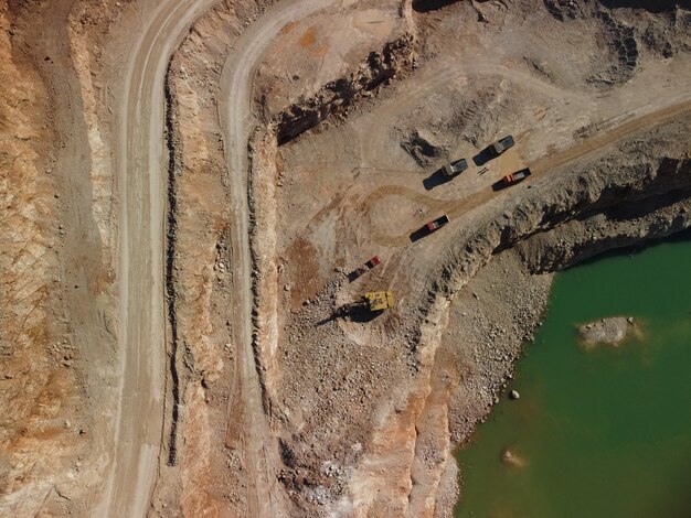 Aerial view of industrial opencast mining quarry with lots of machinery at work extracting fluxes