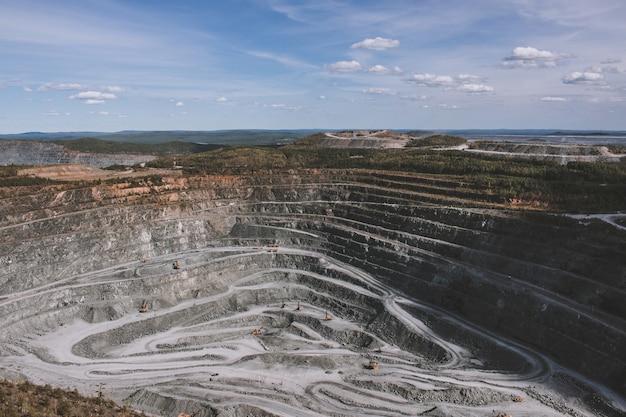 Aerial view industrial of opencast mining quarry with lots of machinery at work - view from above. Extraction of lime, chalk, calx, caol