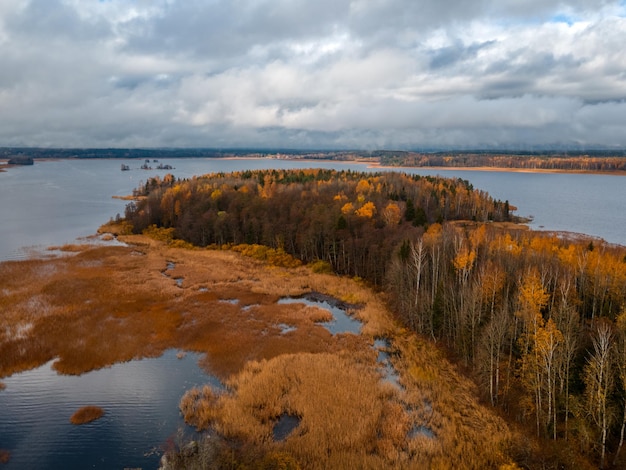 Foto vista aerea dell'isola con alberi con fogliame giallo e arancione nel mezzo del lago. cielo nuvoloso blu. natura del nord. viborg, russia. concetto di viaggio. ambiente puro.