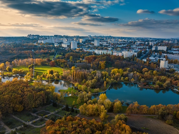 Aerial view of a lake in a park with autumn trees. Kishinev, Moldova. Epic aerial flight over water. Colorful autumn trees in the daytime.