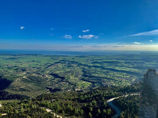 Aerial view of landscape and sea against blue sky