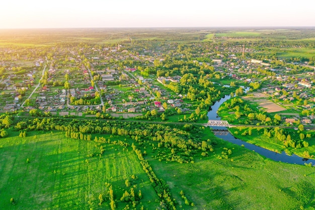 緑の野原の牧草地の上面図の小さな町の小川の中で曲がりくねった小さな川の空撮風景