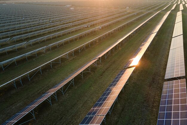 太陽光発電所を空から眺める - 太陽光パネルの列で夕方にクリーンな電力を生産する - ゼロ排出の再生可能電力のコンセプト