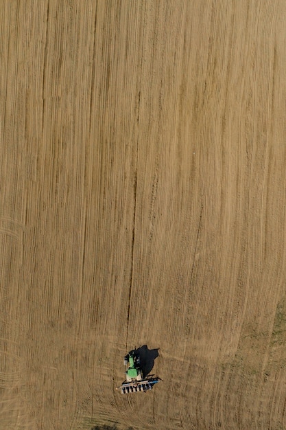 Aerial view large tractor cultivating a dry field.