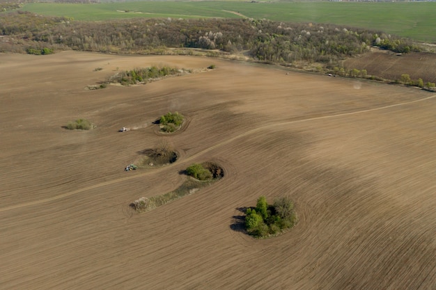 Aerial view large tractor cultivating a dry field.