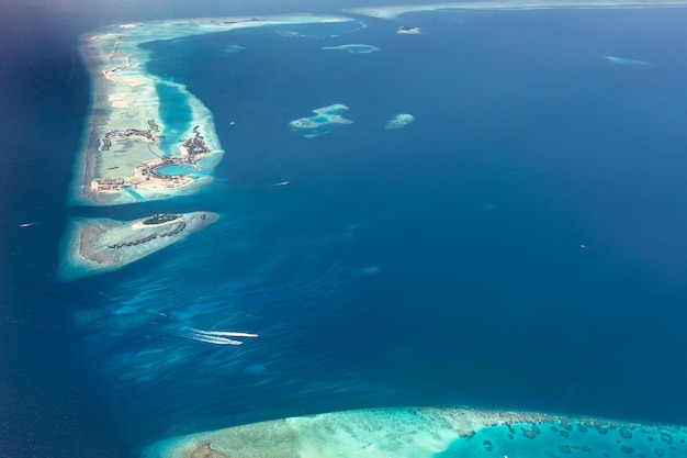 Aerial view of Maldives islands and atolls. Exotic tourism and travel background. Amazing blue sea