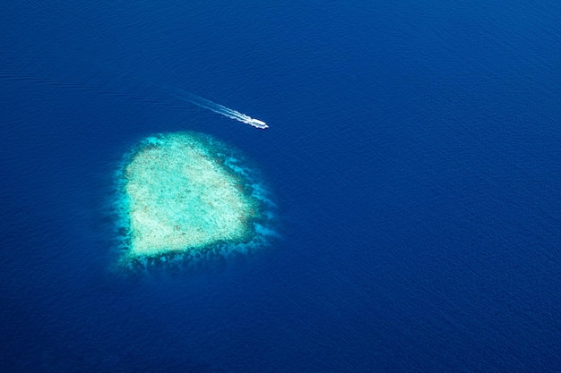 Aerial view of Maldives resort luxury travel destination Boat passing by deep blue ocean reef