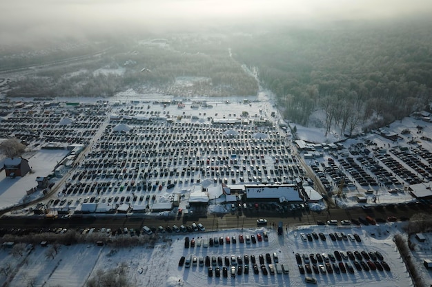 Aerial view of many cars parked for sale and people customers walking on car market or parking lot in winter
