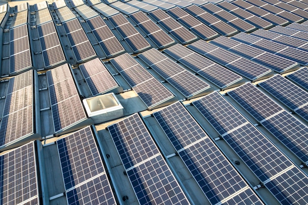 Aerial view of many photo voltaic solar panels mounted of industrial building roof.