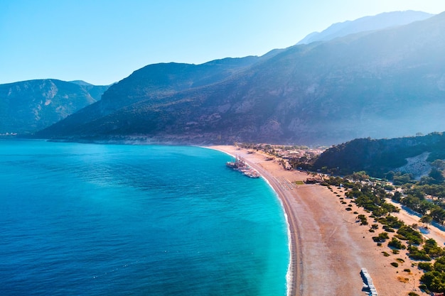 夏の晴れた日に山の砂浜とボートのある地中海湾の空撮トルコのオルデニズにある青いラグーンのドローン写真