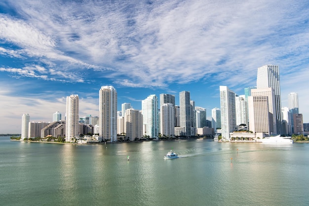 Aerial view of Miami skyscrapers with blue cloudy skywhite boat sailing next to Miami downtown