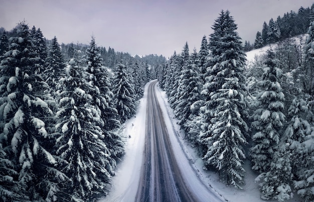 Вид с воздуха на горную дорогу в зимнем лесу