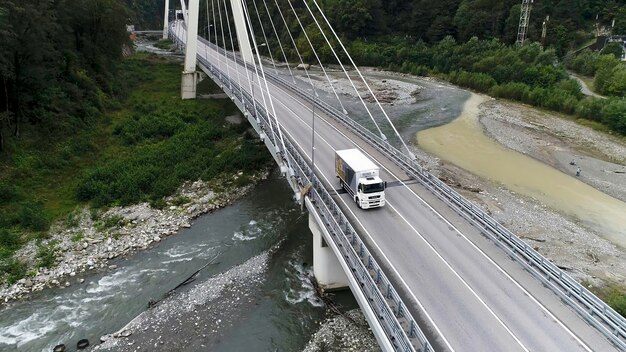 高速道路と貨物の白いトラックの輸送を運転する新しいコンクリート橋の空中景色