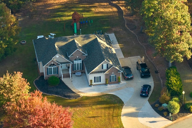 Вид с воздуха на новый семейный дом между желтыми деревьями в пригороде Южной Каролины в осенний сезон Развитие недвижимости в американских пригородах