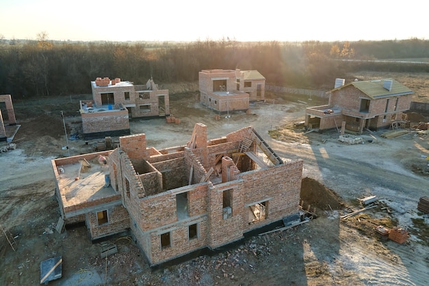 Aerial view of new homes with brick framework walls under construction in rural suburban area Development of real estate in modern city suburbs