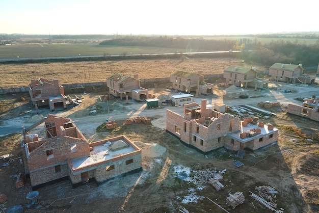 Aerial view of new homes with brick framework walls under construction in rural suburban area Development of real estate in modern city suburbs