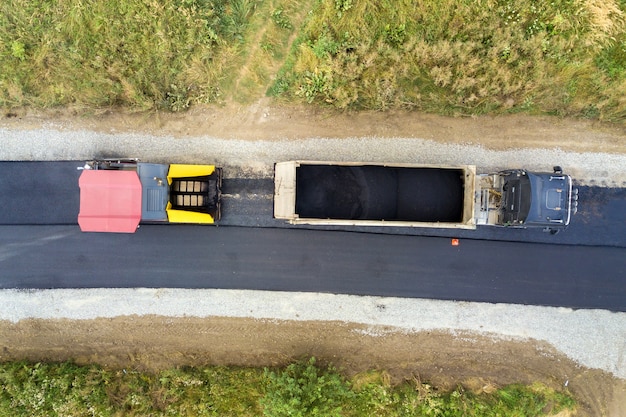 アスファルト敷設機械が稼働している新しい道路建設の航空写真。