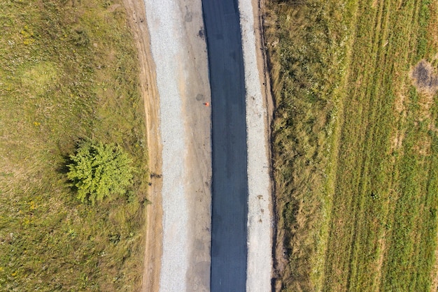 Aerial view of new road construction with newly layed black asphalt lane.