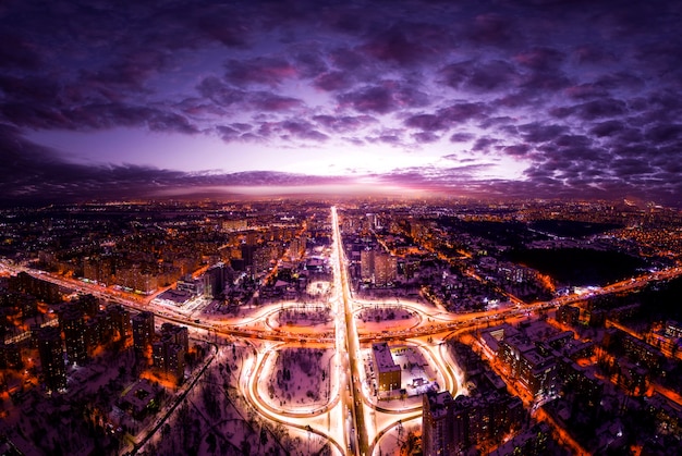 Aerial view of the night city and transport interchange illuminated by lanterns. Dark night sky. 