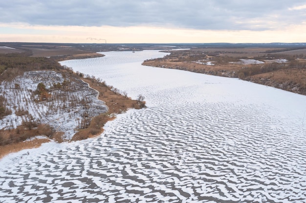 写真 凍った雪の川の空撮冬の風景波の形をした雪が川全体に沿って風に吹き飛ばされた冬の曲がりくねった川を高所から撮影