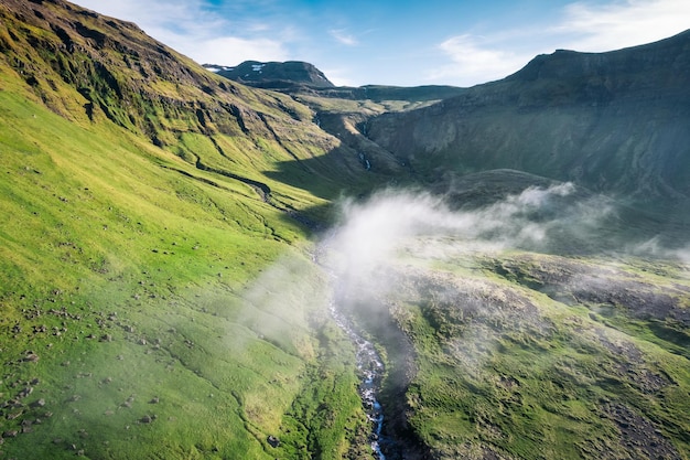 写真 アイスランドの夏の人里離れた荒野に火山と霧のある古代の緑の谷の空撮