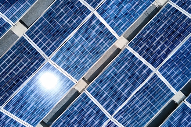 녹색 생태 전기를 생산하기 위해 산업 건물 지붕에 장착된 파란색 태양광 패널의 공중 전망. 지속 가능한 에너지 개념의 생산.