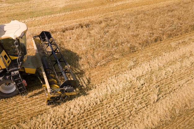 Фото Вид с воздуха на комбайн, собирающий большое поле спелой пшеницы. сельское хозяйство с точки зрения дрона.