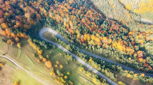 写真 日没時の美しい秋の林道の空撮。トラックの通行がある山の曲がりくねった道