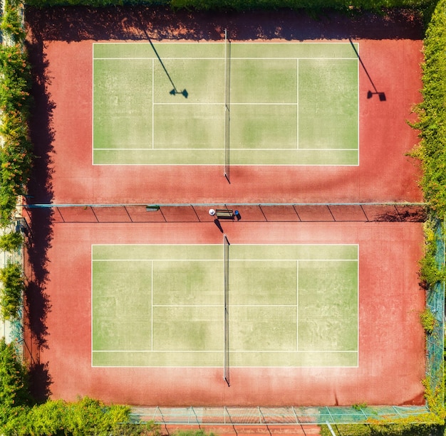 Фото Вид с воздуха на теннисный корт на закате летом вид сверху с летающего дрона на зеленые теннисные корты вид сверху на спортивное тренировочное поле в солнечный яркий день фон и концепция спортивная площадка