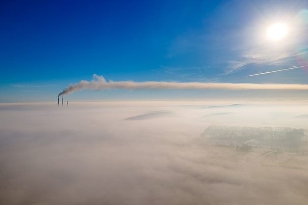 写真 霧の田園地帯と遠くの工場のパイプと冬の風景の空撮