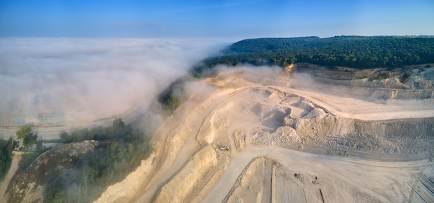 Aerial view of open pit mining of limestone materials for construction industry with excavators and dump trucks