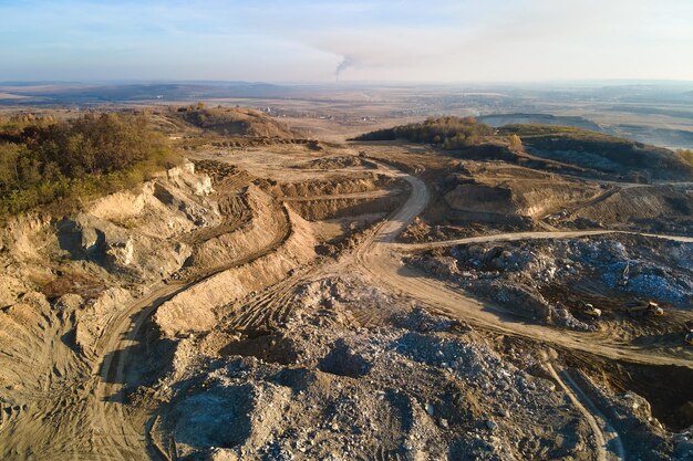 Aerial view of open pit mining site of limestone materials for construction industry with excavators and dump trucks