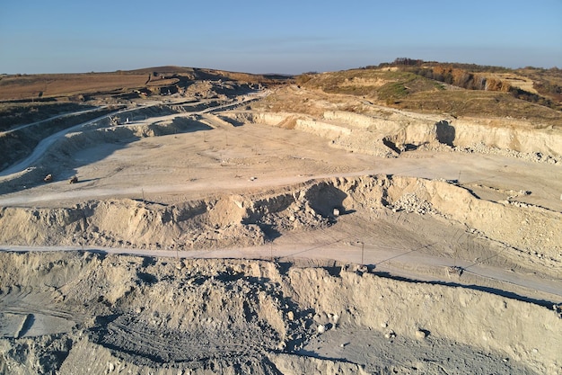 Aerial view of open pit mining site of limestone materials for\
construction industry with excavators and dump trucks