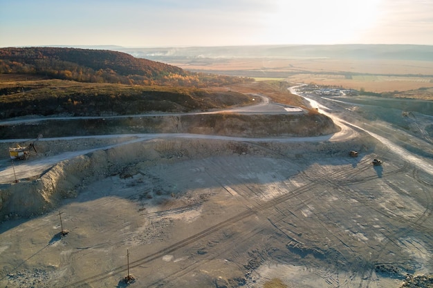 Aerial view of open pit mining site of limestone materials for construction industry with excavators and dump trucks