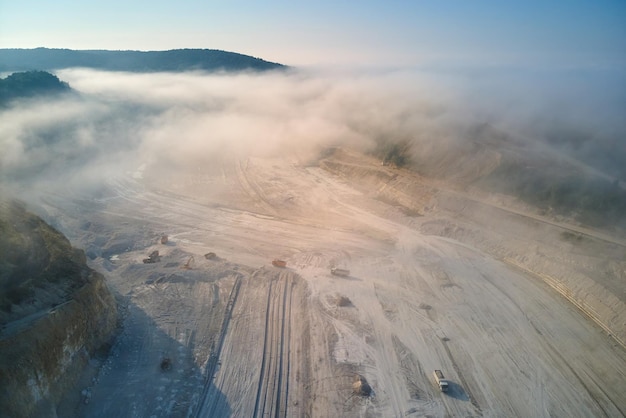 Aerial view of open pit mining site of limestone materials extraction for construction industry with excavators and dump trucks.