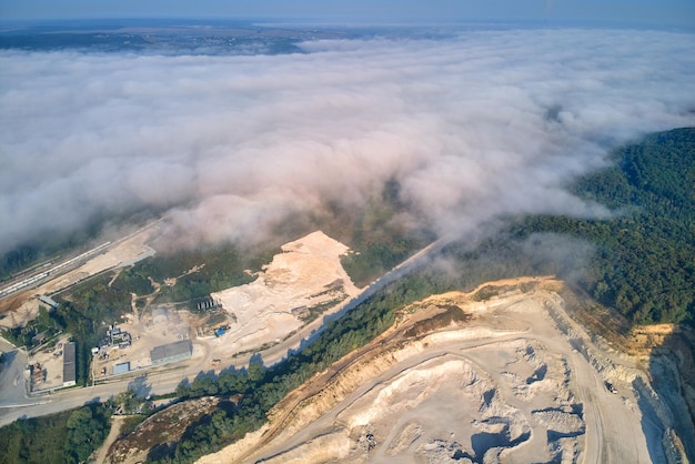 Aerial view of open pit mining site of limestone materials extraction for construction industry with excavators and dump trucks