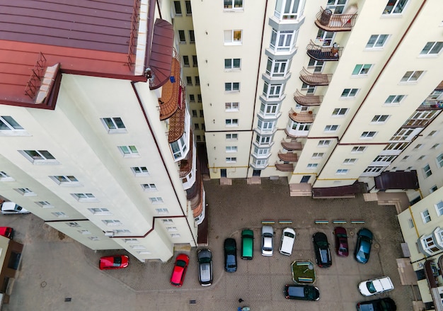 Aerial view of parked cars on parking lot between high apartment buildings.