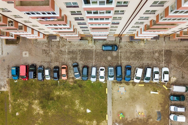 Aerial view of parked cars on parking lot between high apartment buildings.