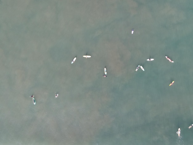 Aerial view of people surfing on waves with surfboards when vacation in Bali Indonesia