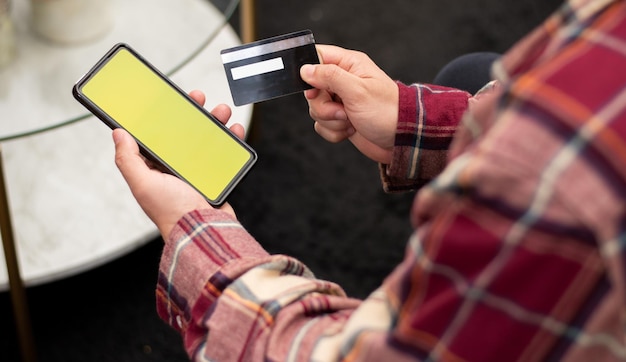 Aerial view of person using cell phone with chroma key holding a credit card in his hand online shopping concept and copy space