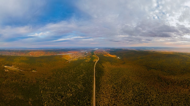 Foto veduta aerea di pittoresche foreste con una strada che attraversa i boschi a distanza si può vedere il villaggio...